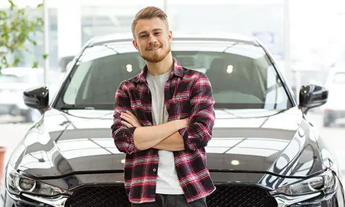 Man standing confidently in front of new car for photo.