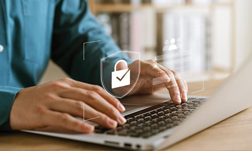 Person sitting at table working on computer with padlock security overlay.